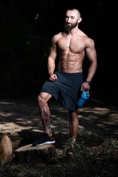 Beard Muscular Man Resting After Exercise Outdoors And Drinking From Shaker