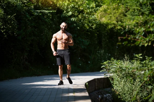 英俊的胡子男人强壮有力地站在户外 树叶的背景 — 图库照片