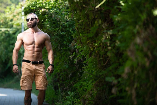 英俊的胡子男人强壮有力地站在户外 树叶的背景 — 图库照片