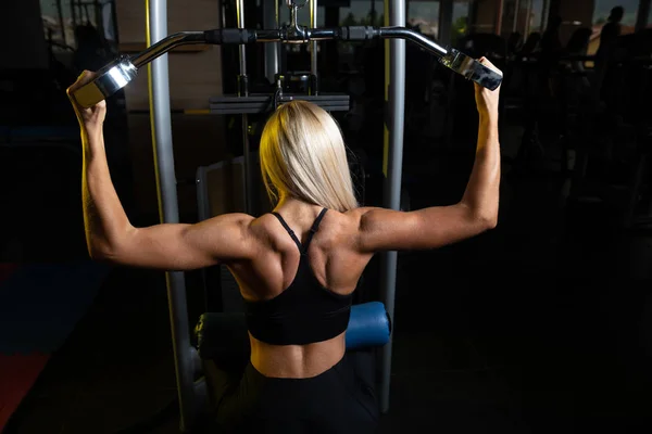 Kvinna Utövar Tillbaka Maskin Gymmet Och Flexar Muskler — Stockfoto