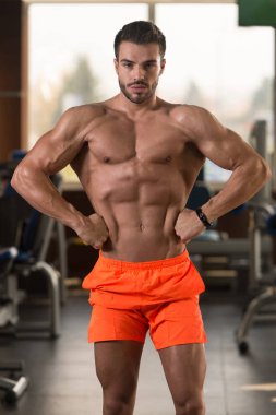 Yakışıklı Genç Adam Spor Salonunda Güçlü Duruyor ve Kaslarını Geriyor - Kas Atletik Vücut Geliştirici Spor Sonrası Spor Pozisyonu