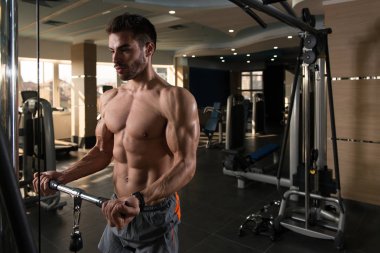 Spor salonundaki adam, spor salonundaki kablolu televizyonuyla bisiklete biniyor.