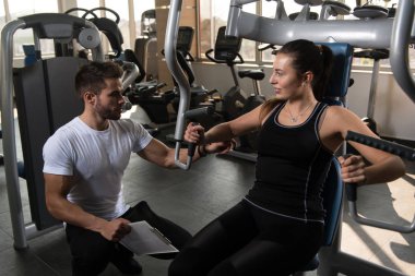 Kişisel antrenör genç kadın gösterilen göğüs spor salonunda tren nasıl