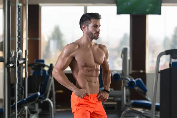 Yakışıklı Genç Adam Spor Salonunda Güçlü Duruyor Kaslarını Geriyor Kas — Stok fotoğraf