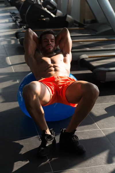 若い男ボディービルのトレーニングの一環としてボールで腹筋のエクササイズを行うアスリート — ストック写真
