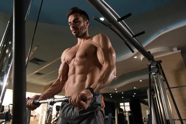 男子在健身房里用缆绳在机器上练习二头肌 — 图库照片
