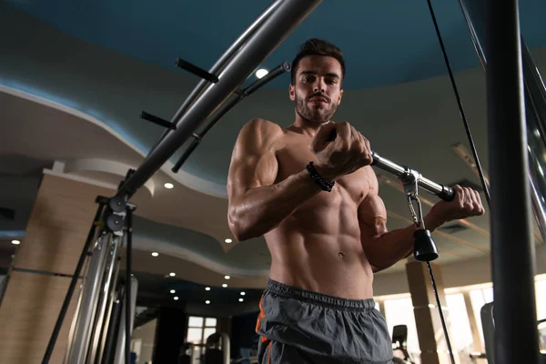 Kas geliştirme vücut geliştiricisi, spor salonunda kablolu TV ile makina üzerinde bisiklet egzersizi yapıyor.