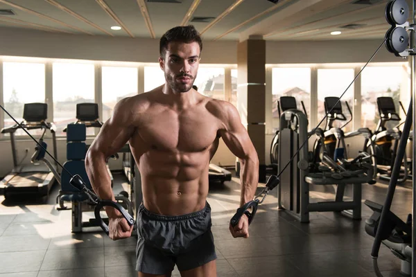 Güzel kaslı vücut geliştirici. Spor salonunda kablolu TV ile Göğüs Üstünde Ağırlık Egzersizi Yapıyor.