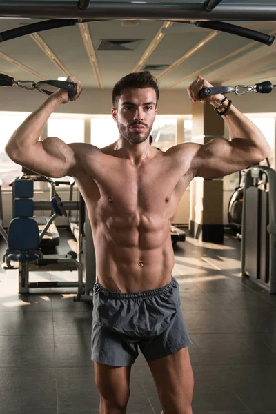 Güzel kaslı vücut geliştirici. Spor salonunda kablolu TV ile Göğüs Üstünde Ağırlık Egzersizi Yapıyor.