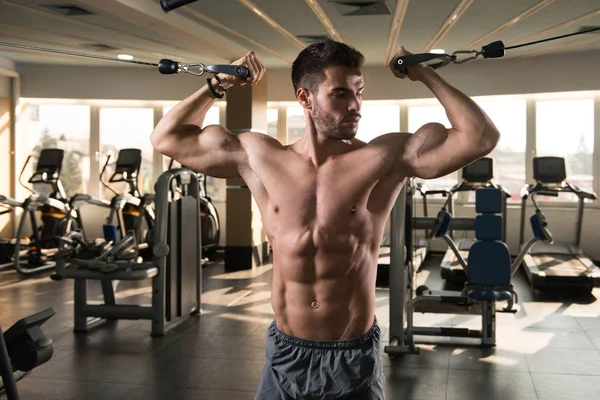 肌肉人做重的重量锻炼为胸口在机器与缆绳在健身房 — 图库照片