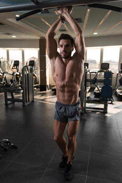 Spor salonu ve kasların esneme - güçlü ayakta sağlıklı genç adam kaslı atletik vücut Fitness Model çalışmaları sonra poz