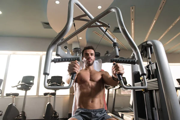 Güzel kaslı vücut geliştirici. Spor salonunda kablolu TV ile Göğüs Üstünde Ağırlık Egzersizi Yapıyor.