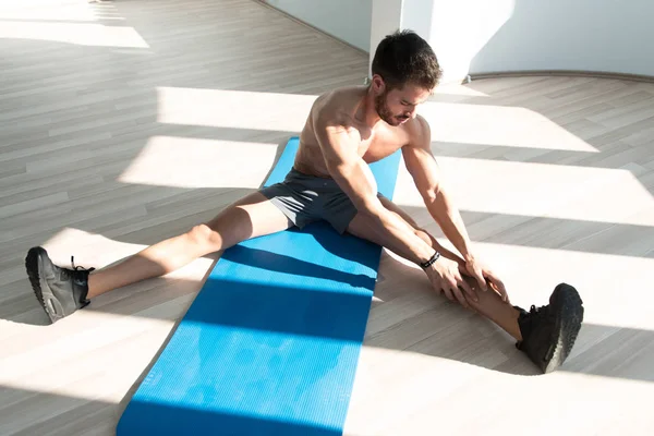 在一间健身房和肌肉伸缩 肌肉运动健美健身模型在地板伸展肌肉男 — 图库照片