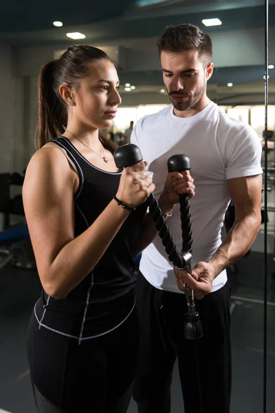 私人教练显示年轻女子如何培养在健身房里的二头肌 — 图库照片