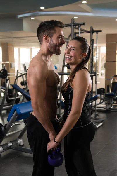 身体适合夫妇的肖像显示他们训练有素的身体与水壶钟 肌肉运动健美健身模型摆在运动后 — 图库照片