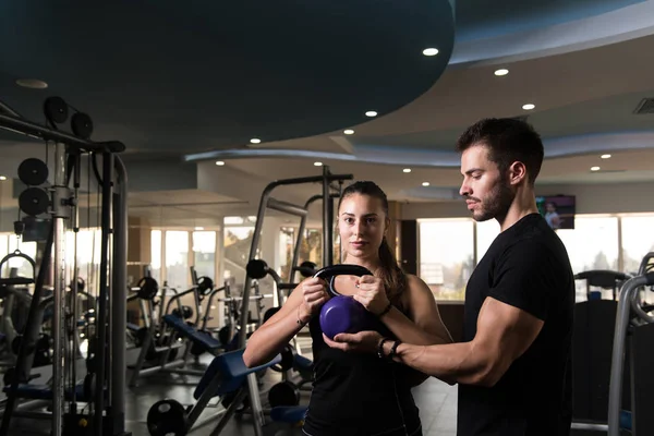 年轻的女人和男人与壶铃在健身房锻炼 — 图库照片