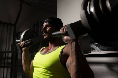 Yakışıklı vücut geliştirmeci için makine omuzlarında ağır egzersiz yaparak