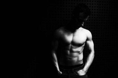 İyi eğitilmiş vücudunu gösteren genç bir adamın portresi mavi kot giyerken - kaslı atletik vücut geliştirici spor modeli pozu duvarın yanındaki duvarda egzersiz yaptıktan sonra - metinleriniz için bir yer