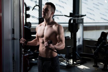 Spor salonundaki adam, spor salonundaki kablolu televizyonuyla bisiklete biniyor.