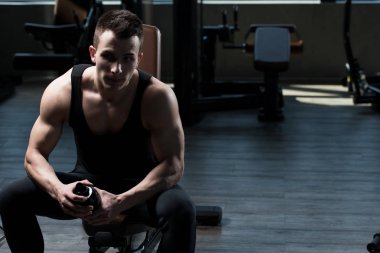 Yakışıklı ve çekici bir genç adam. Vücut kasları spor salonunda dinleniyor.