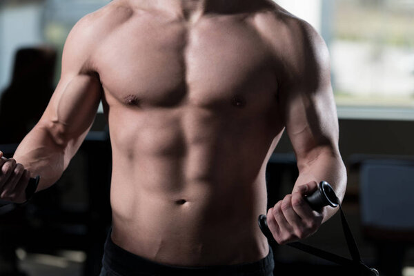 Man In The Gym Exercising On His Biceps On Machine With Cable In The Gym