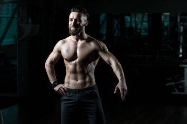 Yakışıklı Genç Adam Spor Salonunda Güçlü Duruyor ve Kaslarını Geriyor - Kas Atletik Vücut Geliştirici Spor Sonrası Spor Pozisyonu