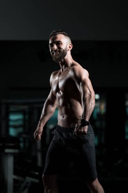Yakışıklı Genç Adam Spor Salonunda Güçlü Duruyor ve Kaslarını Geriyor - Kas Atletik Vücut Geliştirici Spor Sonrası Spor Pozisyonu
