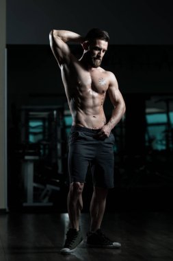 Yakışıklı Genç Adam Spor Salonunda Güçlü Duruyor ve Kaslarını Geriyor - Kas Atletik Vücut Geliştirici Spor Sonrası Spor Pozisyonu