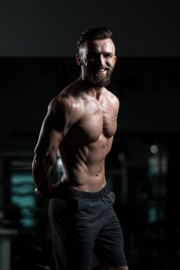 İyi eğitilmiş vücudunu gösteren genç bir adamın portresi - kaslı atletik vücut geliştirici spor sonrası vücut geliştirme modelliği pozu