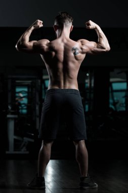 İyi eğitilmiş vücudunu gösteren genç bir adamın portresi - kaslı atletik vücut geliştirici spor sonrası vücut geliştirme modelliği pozu