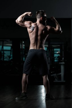 Yakışıklı Genç Adam Spor Salonunda Güçlü Duruyor ve Kaslarını Geriyor - Kas Atletik Vücut Geliştirici Spor Sonrası Spor Pozisyonu