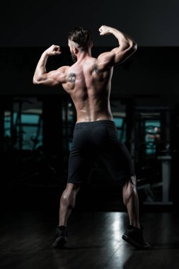 İyi eğitilmiş vücudunu gösteren genç bir adamın portresi - kaslı atletik vücut geliştirici spor sonrası vücut geliştirme modelliği pozu