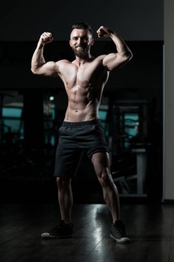 İyi eğitilmiş vücudunu gösteren genç bir adamın portresi - kaslı atletik vücut geliştirici spor sonrası vücut geliştirme modelliği pozu