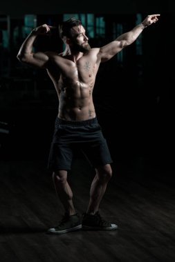 Yakışıklı Genç Adam Spor Salonunda Güçlü Duruyor ve Kaslarını Geriyor - Kas Atletik Vücut Geliştirici Spor Sonrası Spor Pozisyonu