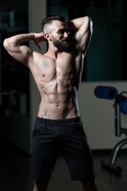 Yakışıklı Genç Adam Spor Salonunda Güçlü Duruyor ve Kaslarını Geriyor - Kas Atletik Vücut Geliştirici Spor Sonrası Spor Pozisyonu