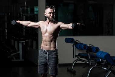 Çalışma dışarı bir spor salonunda Dumbbells ile omuz adam