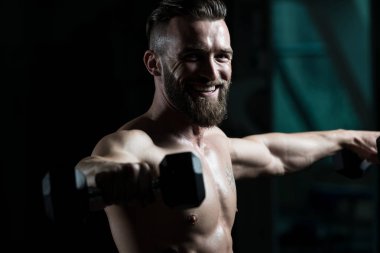 Çalışma dışarı bir spor salonunda Dumbbells ile omuz atlet