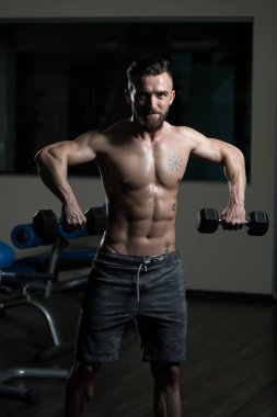 Çalışma dışarı bir spor salonunda Dumbbells ile omuz atlet