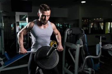 Sırt üstü ağırlıklar ile makine için ağır egzersiz yaparak yakışıklı vücut geliştirmeci