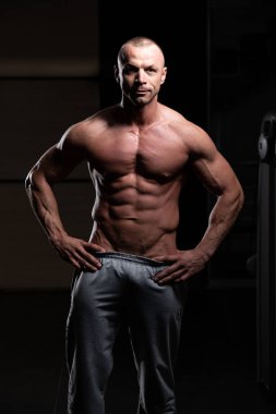 Yakışıklı Genç Adam Spor Salonunda Güçlü Duruyor ve Kaslarını Geriyor - Kas Atletik Vücut Geliştirici Spor Sonrası Spor Pozisyonu