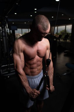 Spor salonundaki adam spor salonunda kablolu TV ile trisepslerini çalıştırıyor.