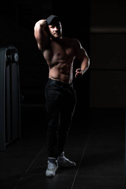 Yakışıklı Genç Adam Spor Salonunda Güçlü Duruyor ve Kaslarını Geriyor - Kas Atletik Vücut Geliştirici Spor Sonrası Spor Pozisyonu