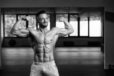 Yakışıklı Genç Adam Spor Salonunda Güçlü Duruyor ve Kaslarını Geriyor - Kas Atletik Vücut Geliştirici Spor Sonrası Spor Pozisyonu