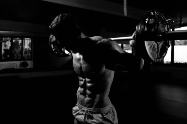 Spor salonundaki güçlü adam halterle bacak egzersizi yapıyor kaslı atletik vücut geliştirici spor mankeni egzersizi.