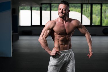 Yakışıklı Genç Adam Spor Salonunda Güçlü Duruyor ve Kaslarını Geriyor - Kas Atletik Vücut Geliştirici Spor Sonrası Spor Pozisyonu