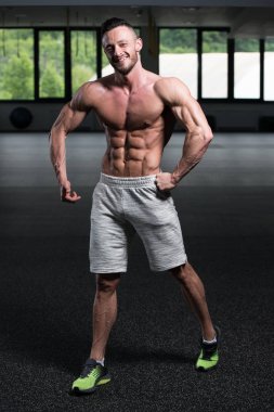 Yakışıklı Genç Adam Spor Salonunda Güçlü Duruyor ve Kaslarını Geriyor - Kas Atletik Vücut Geliştirici Spor Sonrası Spor Pozisyonu
