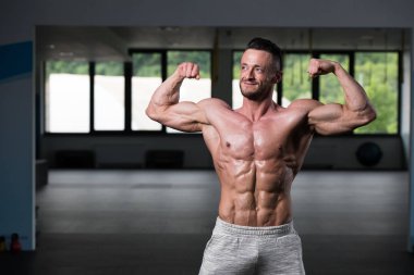 Yakışıklı Genç Adam Spor Salonunda Güçlü Duruyor ve Kaslarını Geriyor - Kas Atletik Vücut Geliştirici Spor Sonrası Spor Pozisyonu