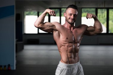 İyi eğitilmiş vücudunu gösteren genç bir adamın portresi - kaslı atletik vücut geliştirici spor sonrası vücut geliştirme modelliği pozu