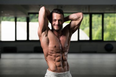 İyi eğitilmiş vücudunu gösteren genç bir adamın portresi - kaslı atletik vücut geliştirici spor sonrası vücut geliştirme modelliği pozu