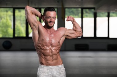 İyi eğitilmiş vücudunu gösteren genç bir adamın portresi - kaslı atletik vücut geliştirici spor sonrası vücut geliştirme modelliği pozu